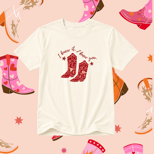 White t-shirt with red cowboy boot design and text on a pink background with boot illustrations.