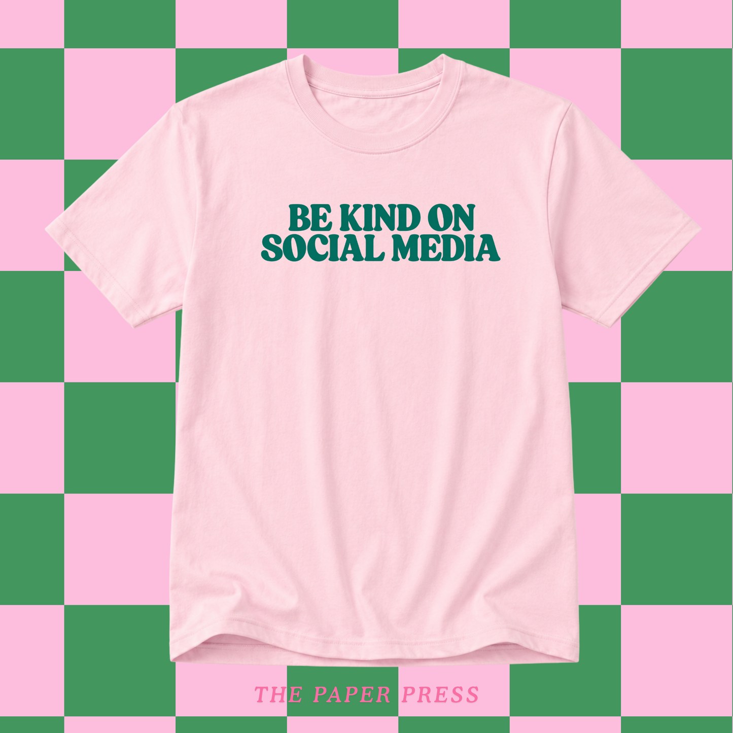 Baby pink slogan t-shirt that says be kind on social media in retro dark green font.