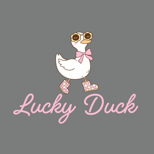Grey t-shirt with cute duck illustration wearing sunglasses, bow, and pink boots, with slogan Lucky Duck in pink script.