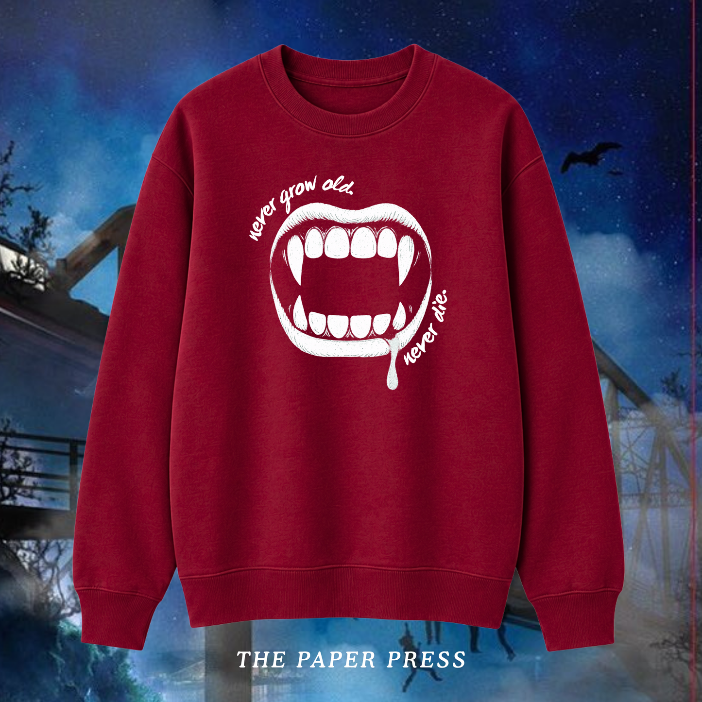 Lost Boys coded red sweater featuring a white vampire fang graphic and “Never Grow Old, Never Die” slogan, hand printed by The Paper Press.