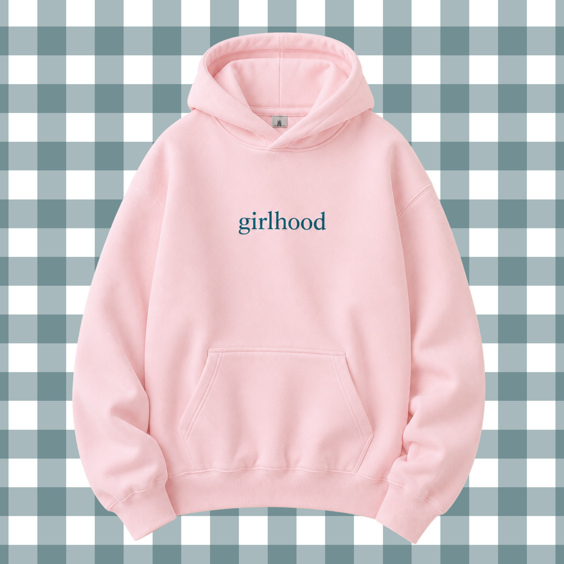 A light pink pullover hoodie with the word 'girlhood' printed in dark teal text on the chest, displayed against a blue and white gingham checkered background.