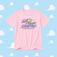 Pink t-shirt with 'Planet Swiftie' logo on a blue background with cloud patterns