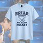 White t-shirt with 'BRIAR UNIVERSITY HOCKEY' text and graphics on a blurred background
