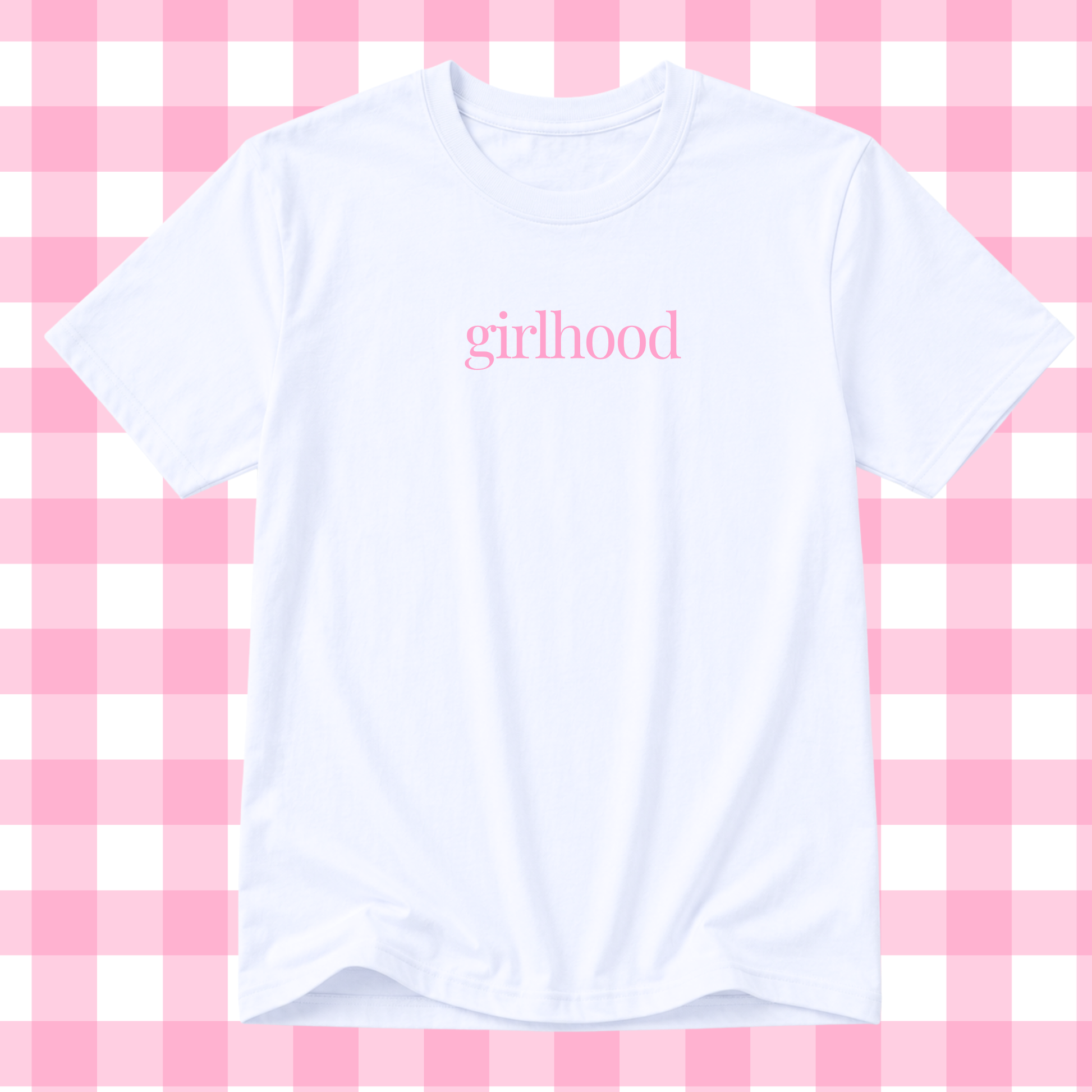 A white short-sleeve crewneck t-shirt with the word 'girlhood' printed in pink lowercase serif text across the chest, displayed against a pink and white checkered background.