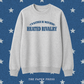 A light heather gray crewneck sweatshirt with blue text reading 'I'D RATHER BE WATCHING HEATED RIVALRY' on the chest, displayed against a blue background with white stars and the text 'THE PAPER PRESS' at the bottom.