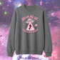 A dark gray crewneck sweatshirt featuring a pink graphic of a UFO, a person falling into a beam of light, and the text 'BEAM ME UP, THIS PLACE SUCKS'. The sweatshirt is displayed against a colorful pink and purple galaxy background, with 'THE PAPER PRESS' text at the bottom.