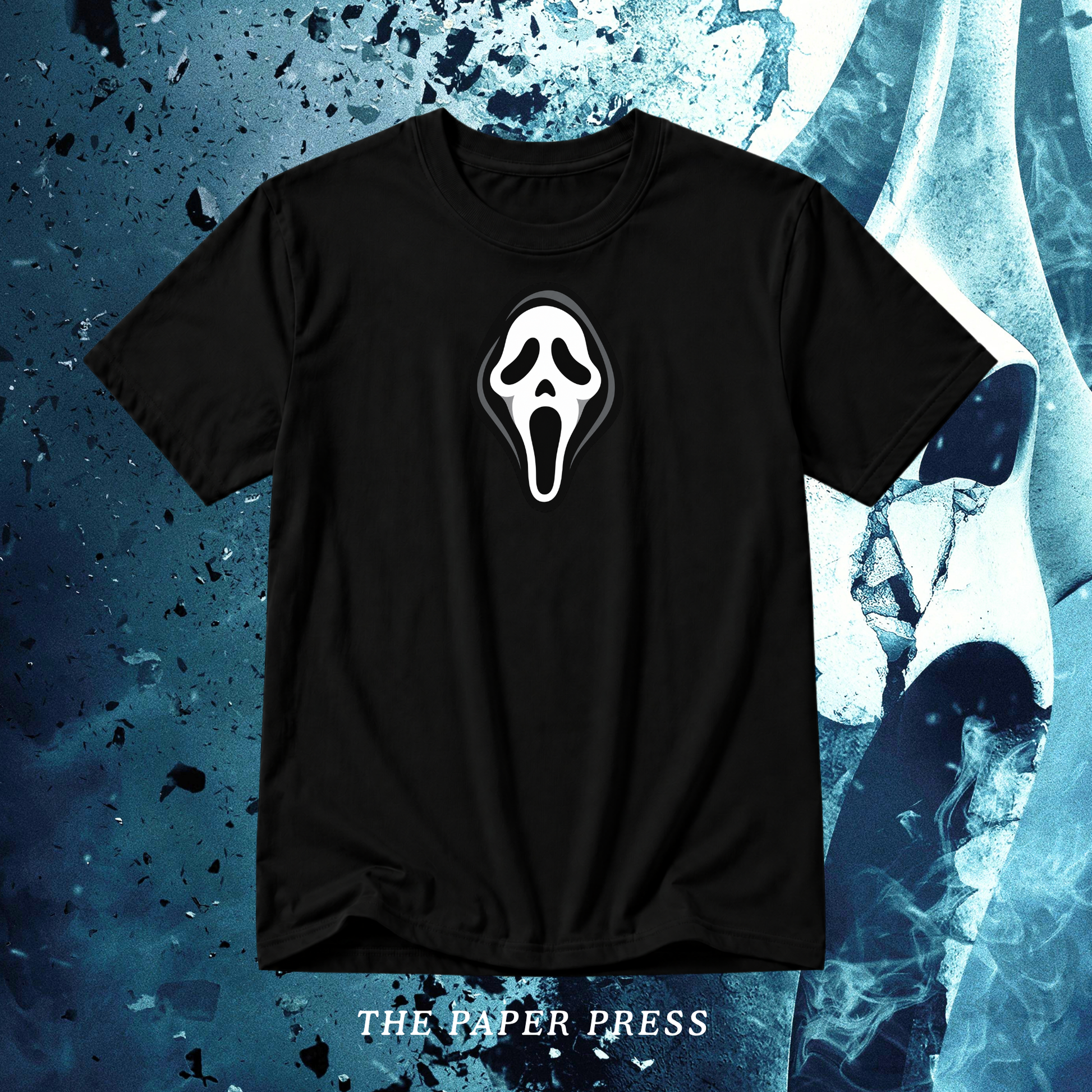 A black short-sleeve t-shirt featuring a white Ghostface mask graphic on the chest, displayed against a dark blue textured background with the text 'THE PAPER PRESS' at the bottom.